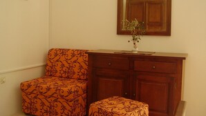 A room with a wooden cabinet, a mirror, and a patterned chair. - Holiday Home Ivas (Milna)
