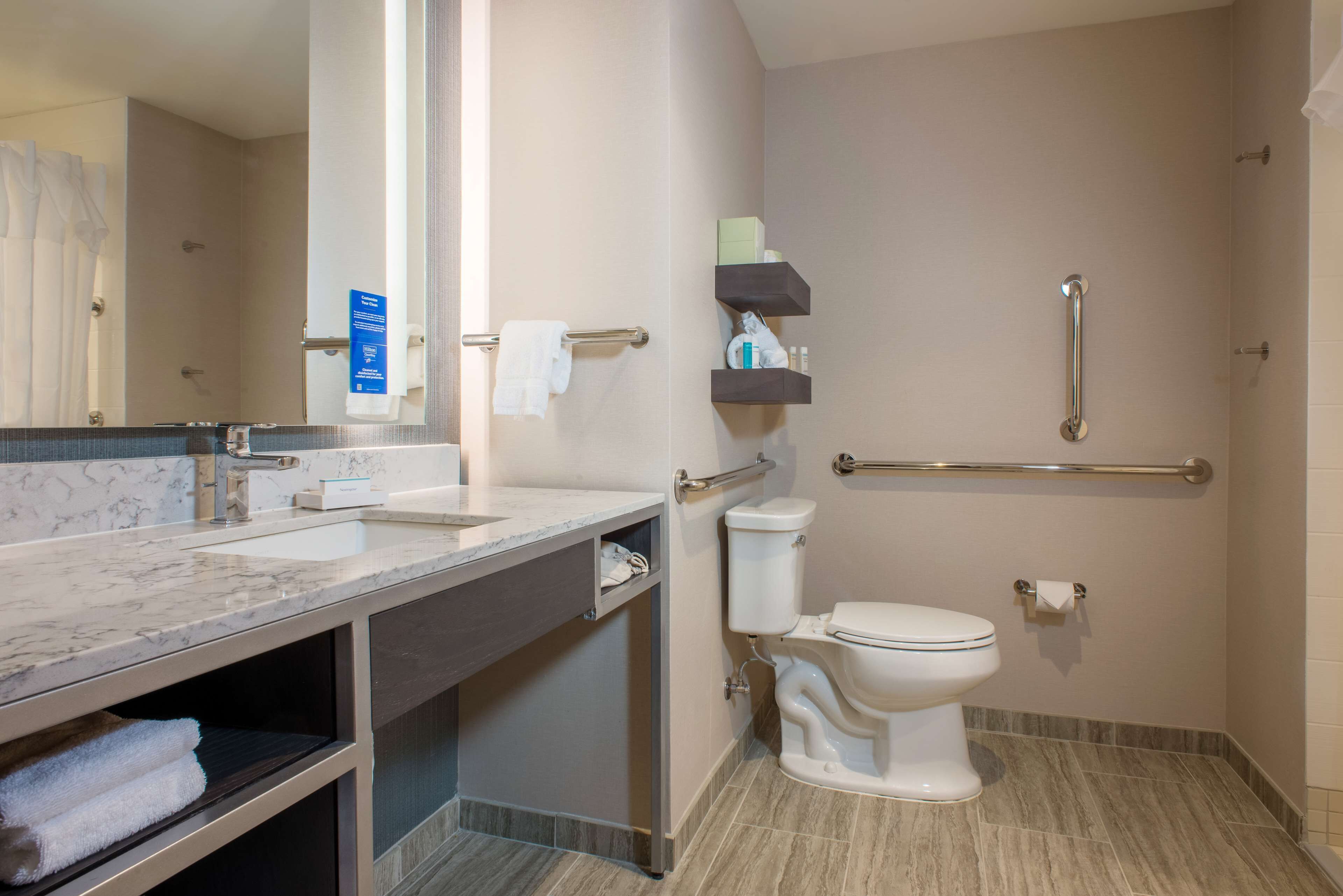 A modern bathroom with a marble sink, a toilet, and a shower area.