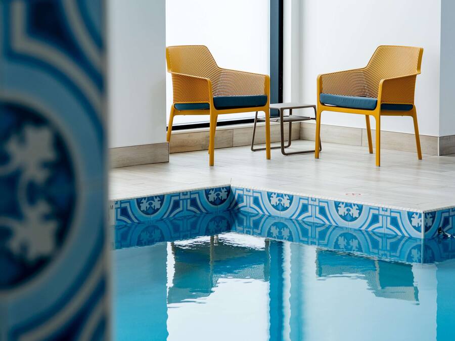 Un área de piscina con dos sillas y una mesa.