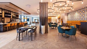 A modern restaurant interior with a bar area, dining tables, and chairs. - Hilton Garden Inn Moncton, NB (Moncton)