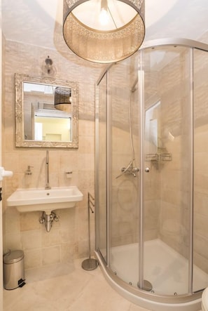 A bathroom with a glass-enclosed shower, a sink with a mirror above it, and a hanging light fixture. - Top luxury experience with villa Monte (Buje)