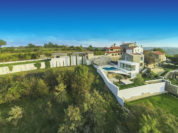 A modern villa with a swimming pool, surrounded by lush greenery and stone walls. - Top luxury experience with villa Monte (Buje)