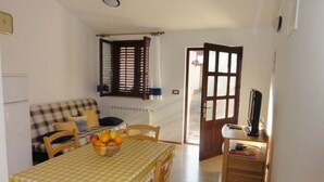 A dining area with a checkered tablecloth, wooden chairs, and a fruit bowl. - Affordable apartment Helena (Medulin)