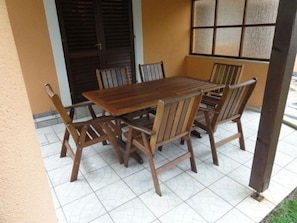 A wooden table with six chairs in an outdoor setting.
