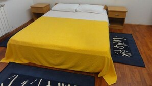 A bed with a yellow bedspread, two bedside tables, and a wall-mounted light fixture. - Affordable apartment Helena (Medulin)
