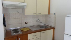 A compact kitchen with a stove, sink, and cabinets. - Affordable apartment Helena (Medulin)