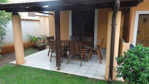 A covered patio with a table and chairs, a potted plant, and a door to the building. - Affordable apartment Helena (Medulin)