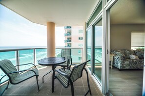 A balcony with a table and chairs, a sofa, and a view of the ocean.