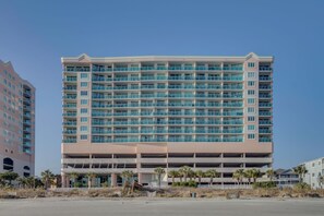 A multi-story hotel with a flat roof, numerous balconies, and a parking garage below.