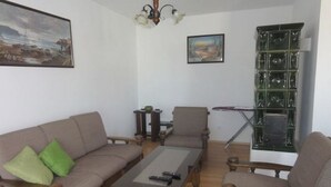 Un salon comprenant un canapé, des fauteuils, une table basse, une bibliothèque et un tableau accroché au mur.