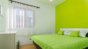 Un dormitorio con cama, mesita de noche, ventana con cortinas y una pared de color verde brillante.