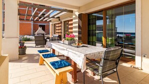 Un patio exterior con una mesa, sillas y una parrilla.