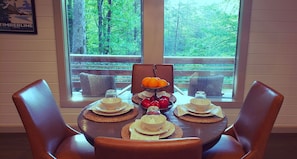 A dining table set with plates, bowls, and a fruit bowl, with chairs around it.