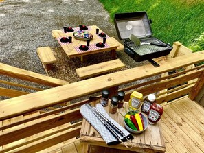 An outdoor dining area with a grill, picnic table, and various condiments.