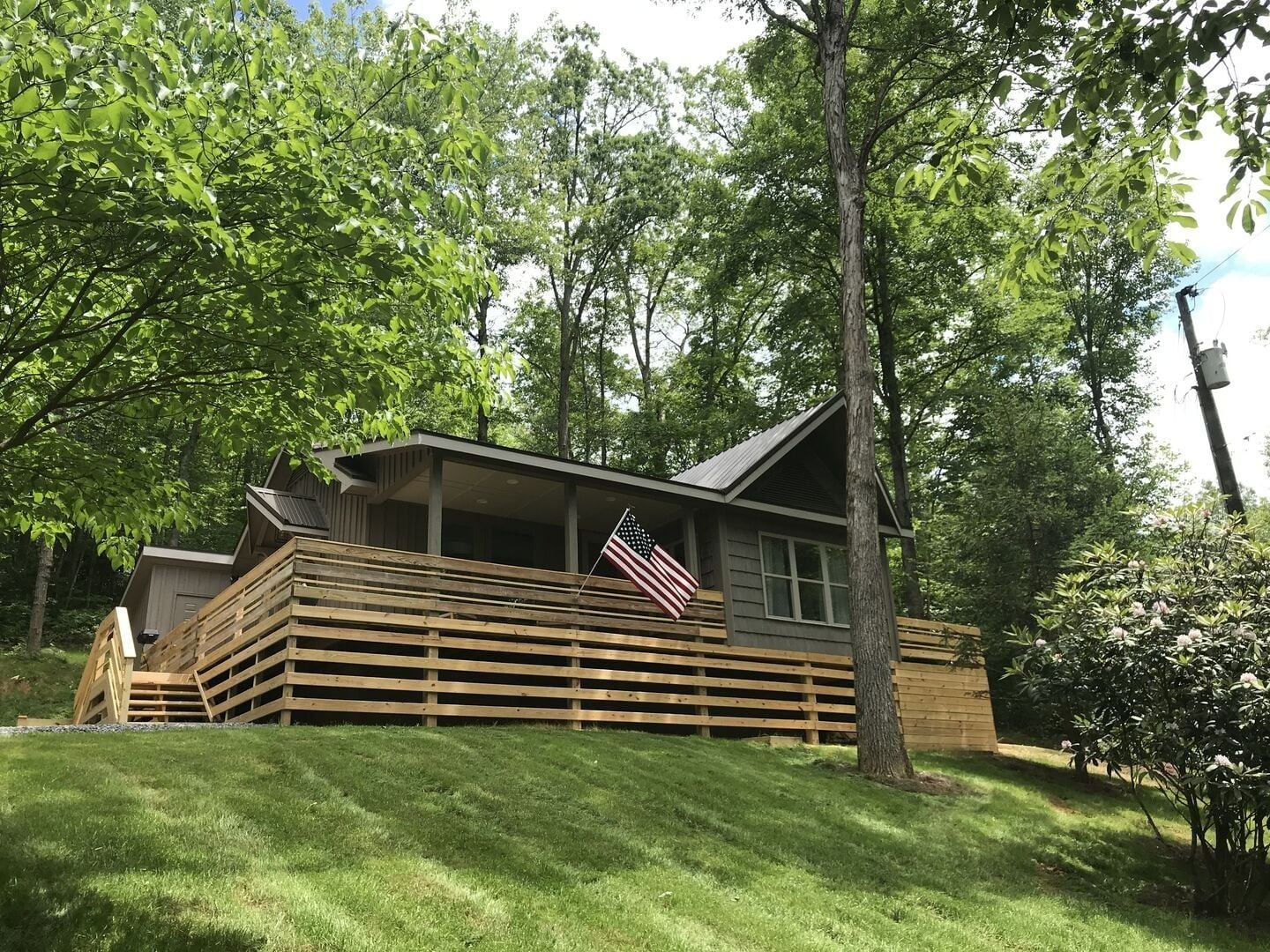 Eine Holzhütte mit einer Holzterrasse, einer Veranda und einer US-amerikanischen Flagge.