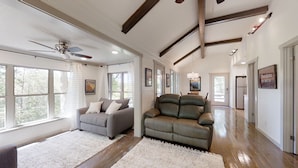 A spacious living room with a grey sofa, a leather armchair, and a ceiling fan. - Happy Camper 1 Bedroom Cottage by RedAwning (Sevierville)