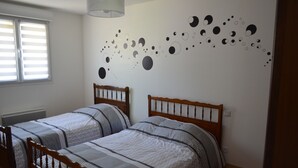 A bedroom with two wooden beds, a wall mural of celestial bodies, and a window with blinds. - Gite Baie de Somme 80  (Pendé)