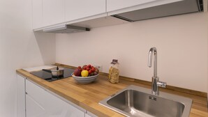 A modern kitchen with a wooden countertop, stainless steel sink, and white cabinets. - Design Holiday Home in Sorrento city center (Sorrento)