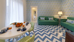 A modern living room with a green sofa, a dining table with orange fruit, and a patterned floor. - Luxury Four Bedroom Home (Sorrento)