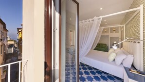 A bedroom with a bed, a green sofa, a desk with a lamp, and a patterned floor. - Luxury Four Bedroom Home (Sorrento)