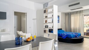 Una sala moderna con comedor, un sofá y una estantería.