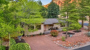 A small house with a porch, surrounded by a garden with various plants and a rock border. - Meadow Lark Trail 3BD 2BA W/ Jacuzzi in THE best location (Sedona)