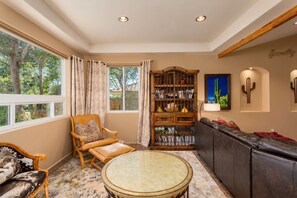 A cozy living room with a wooden bookshelf, leather sofa, and a round glass table.