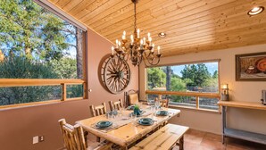 A dining area with a wooden table set for six, surrounded by wooden chairs. - Meadow Lark Trail 3BD 2BA W/ Jacuzzi in THE best location (Sedona)