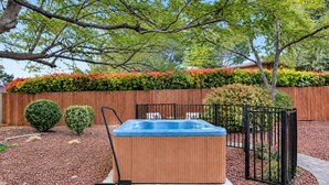 A hot tub in a landscaped garden with a wooden fence, potted plants, and a brick pathway. - Meadow Lark Trail 3BD 2BA W/ Jacuzzi in THE best location (Sedona)