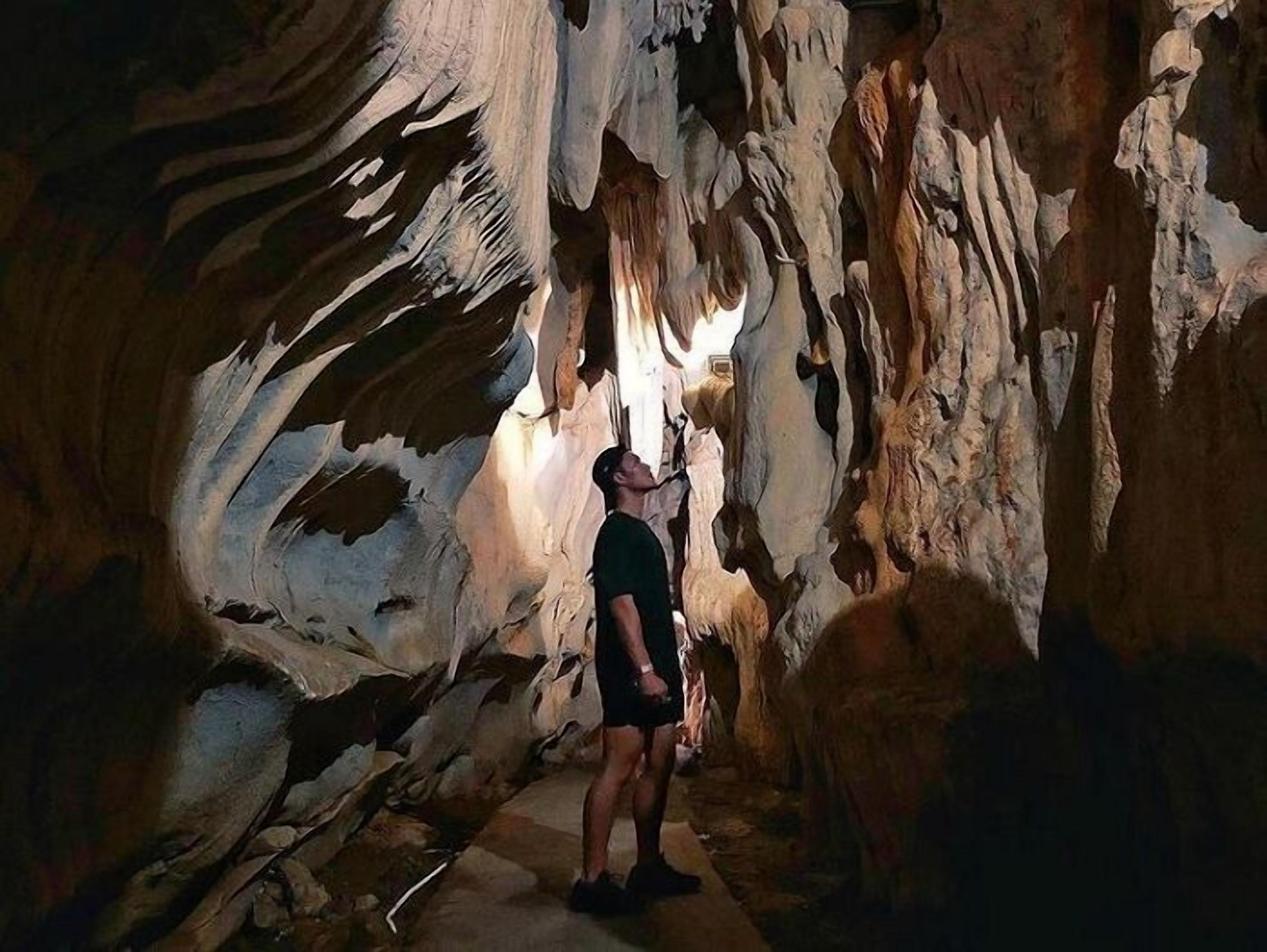 A person standing in a cave with natural rock formations.