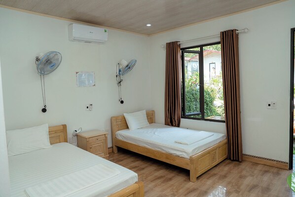 A bedroom with two beds, a window with curtains, an air conditioner, and two wall fans. - Tran Chau Garden Home (Hai Phong)