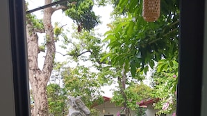 A view from a balcony with a stone-tiled floor, a wooden chair, and a garden with rocks, grass, and trees. - Tran Chau Garden Home (Hai Phong)