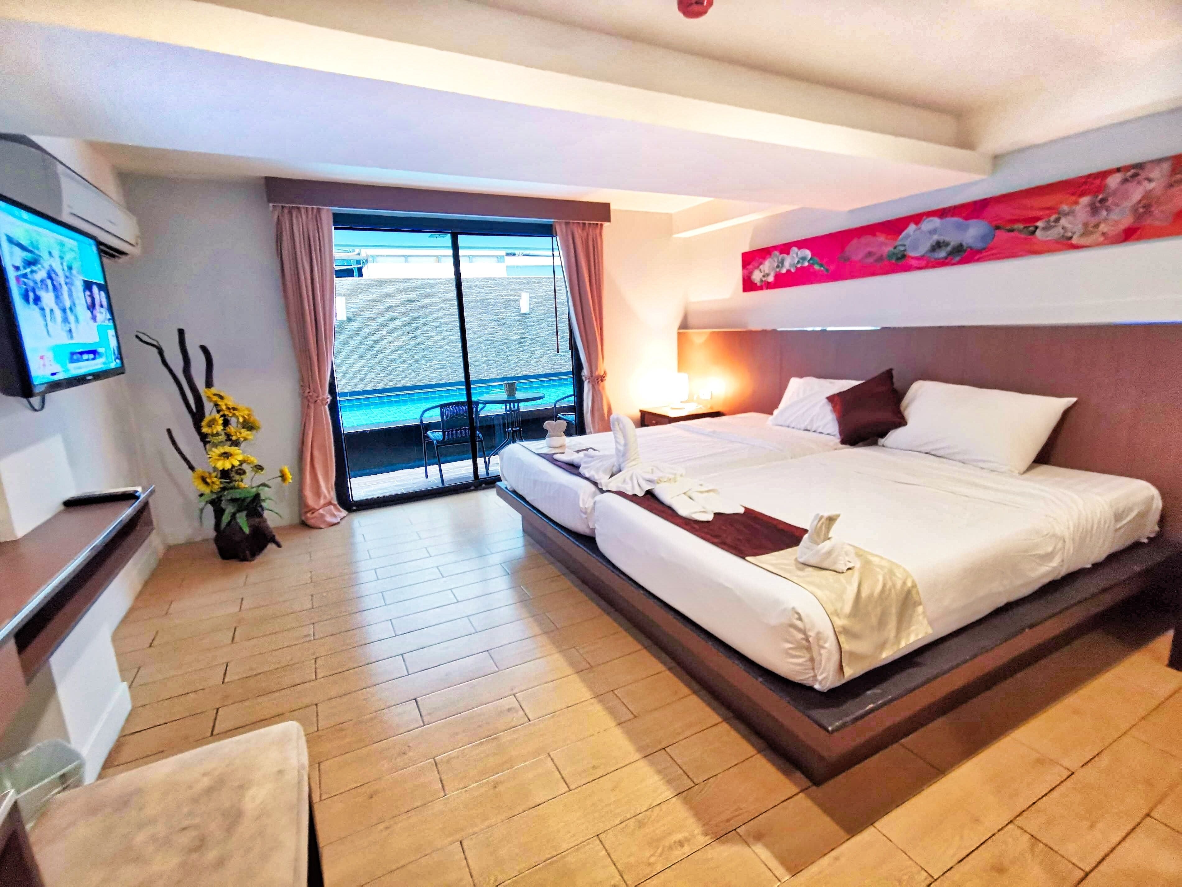 Een hotelkamer met een groot bed, een televisie, een balkon met uitzicht op het water en een schilderij aan de muur.