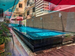 A swimming pool with a tiled edge, surrounded by a pebble-lined deck and potted plants. - Scandia Beach Hotel - Soi 7 Best Location - 200m to Beach next to Food Market (Pattaya)