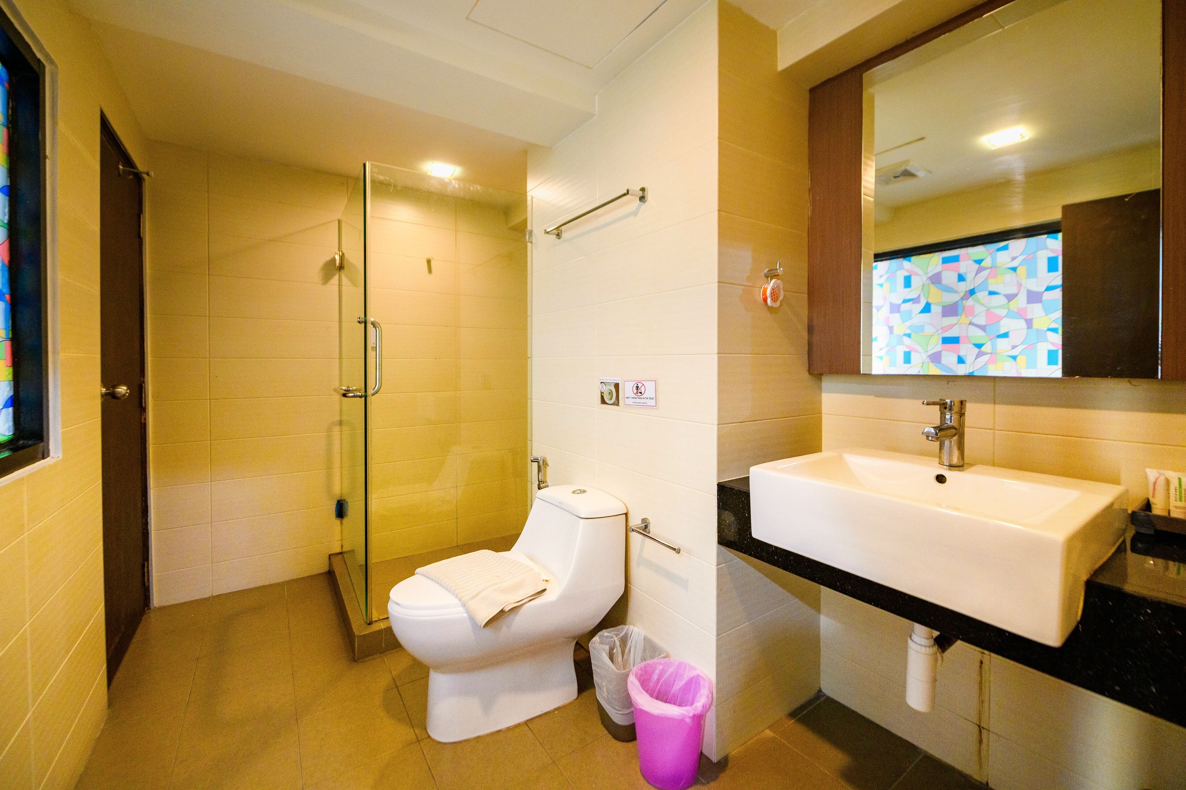 Une salle de bain comprenant des toilettes, une douche à parois de verre, un lavabo et un miroir.