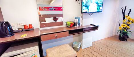 Une chambre d’hôtel équipée d’un lit, d’un bureau, d’une télévision, d’une poubelle et d’un petit tabouret.