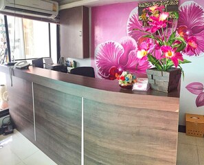 A reception desk with a modern design, a telephone, and a vase with flowers. - Scandia Beach Hotel - Soi 7 Best Location - 200m to Beach next to Food Market (Pattaya)