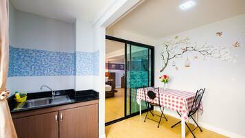 Una cocina moderna con un lavamanos y armarios, un comedor con mesa y sillas, y un mural decorativo en la pared.