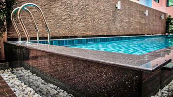 A swimming pool with a stone wall and metal handrails.