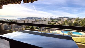 Ein Balkon mit Blick auf ein Schwimmbecken und umliegende Gebäude.