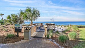 A pathway leading to a beach with palm trees and a wooden boardwalk. - Adagio A101 | Private Beach | Ground Floor Unit | 2 pools | Bonus Bunk Room!! (Santa Rosa Beach)