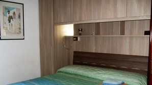 A bedroom with a wooden headboard, a green bedspread, and a framed picture on the wall. - House Yanina (Bellano)