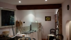 Cocina compacta con fregadero, estufa y refrigerador. Una mesa de comedor con sillas está ubicada cerca de la cocina.