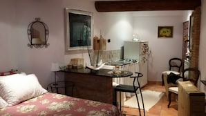 Una cocina compacta con comedor, una cama con ropa de cama floral y un espejo en la pared.