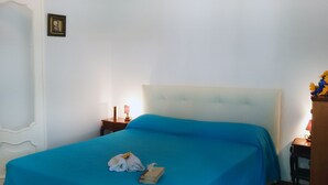 A neatly made bed with a blue bedspread, a folded towel, and a book on the bed.