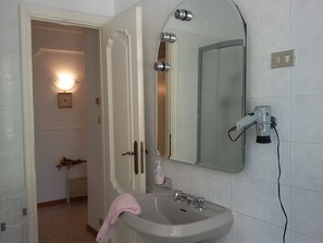 A bathroom with a white sink, a mirror, and a hairdryer on the wall. - Casa Anna (Bogliasco)