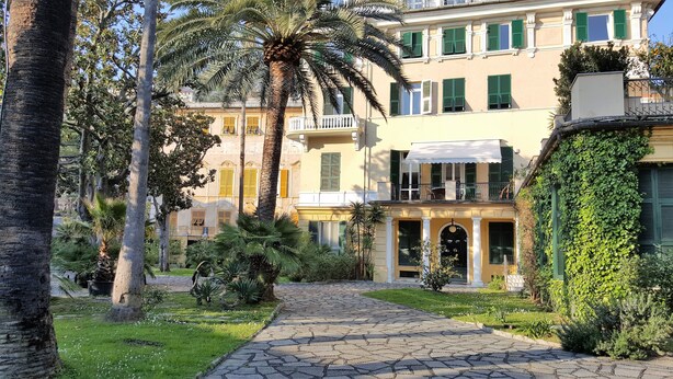 A courtyard with a cobblestone path leading to a building with a balcony and a covered entrance. - Casa Vicki (Genoa)