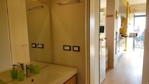 A bathroom with a sink, mirror, and towel rack. There are two light switches on the wall.