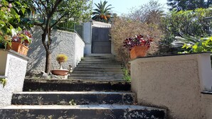 A set of outdoor stairs leading up to a gated entrance, surrounded by potted plants and trees. - Casa Agrumeto (Genoa)