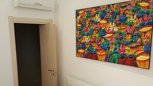 A bedroom with a bed, a door, and a colorful painting on the wall. - House Sole (Genoa)